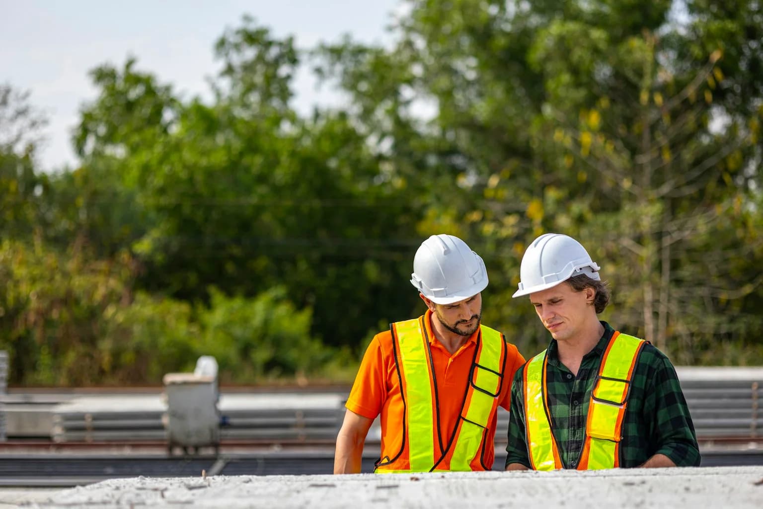 Two construction engineers in hard hats inspecting a concrete production site