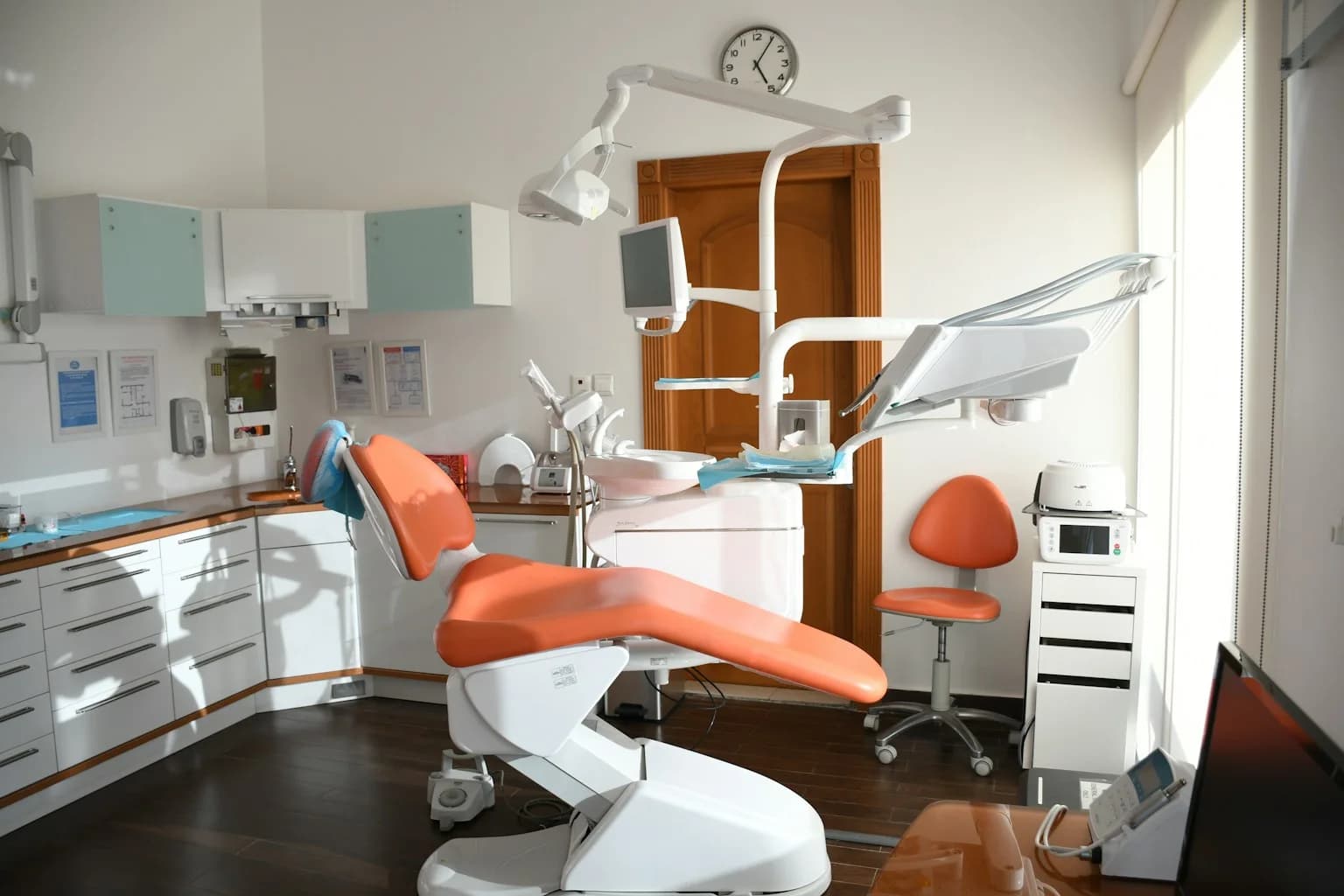 Orange dental chair, examination light and equipment inside a bright treatment room