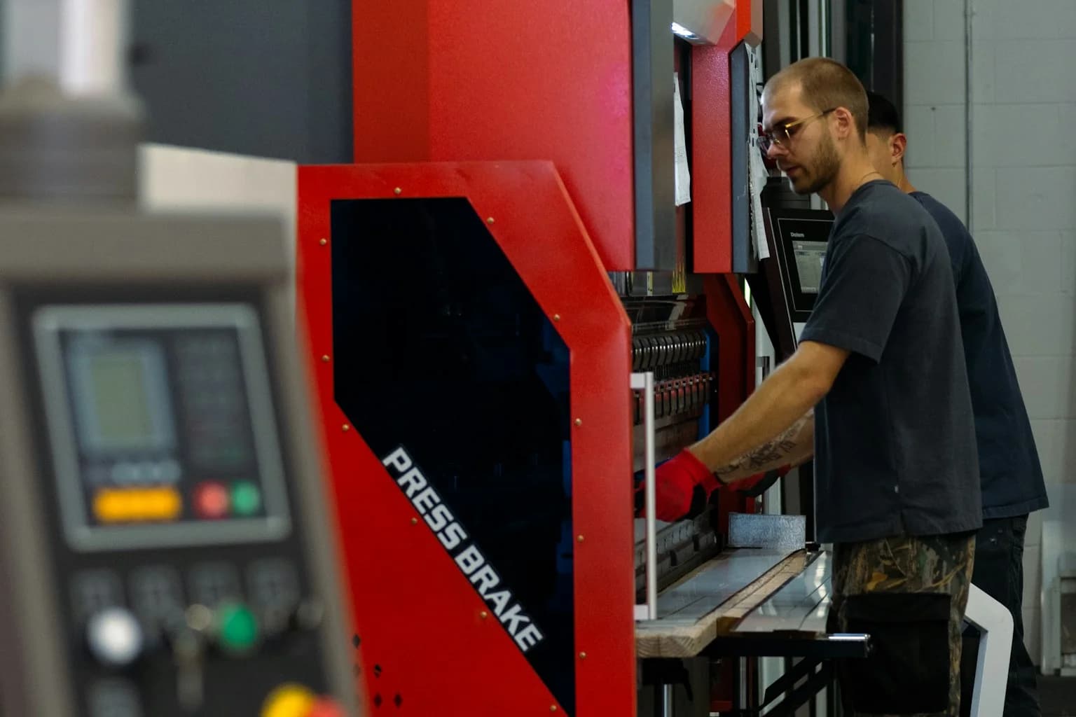 Worker operating a metalworking machine inside a manufacturing workshop